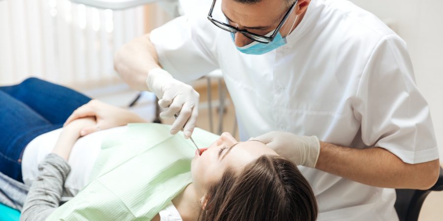 Professional dentist doing teeth checkup on female patient dental surgery